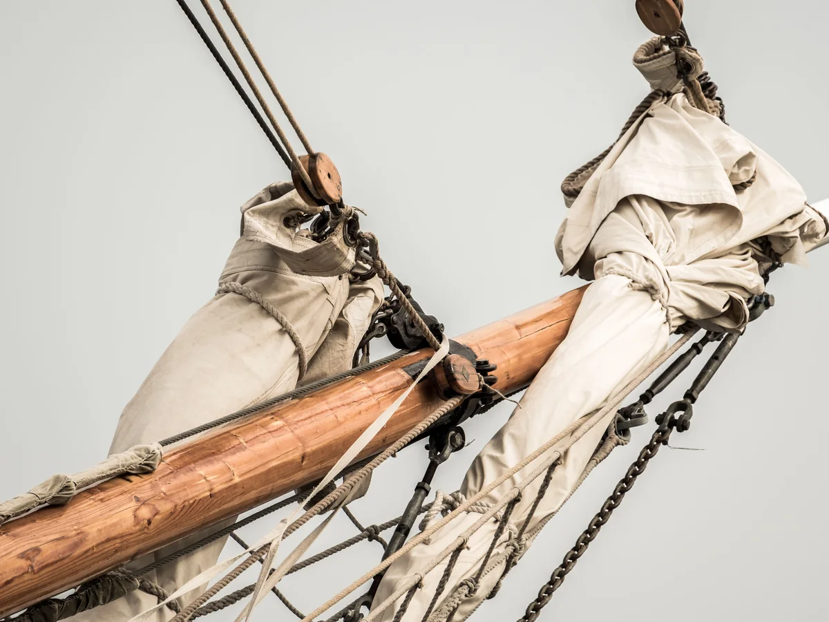 Furled sail and rope rigging on a tall ship's mast — representative of the rigging staged above the theatre's tables, not the venue itself